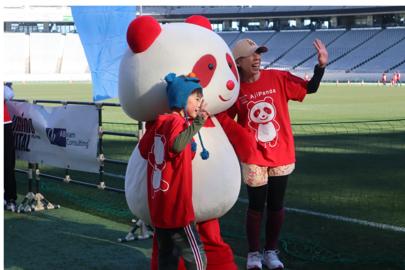 味の素スタジアムのグラウンドで参加者とふれあうアジパンダ 