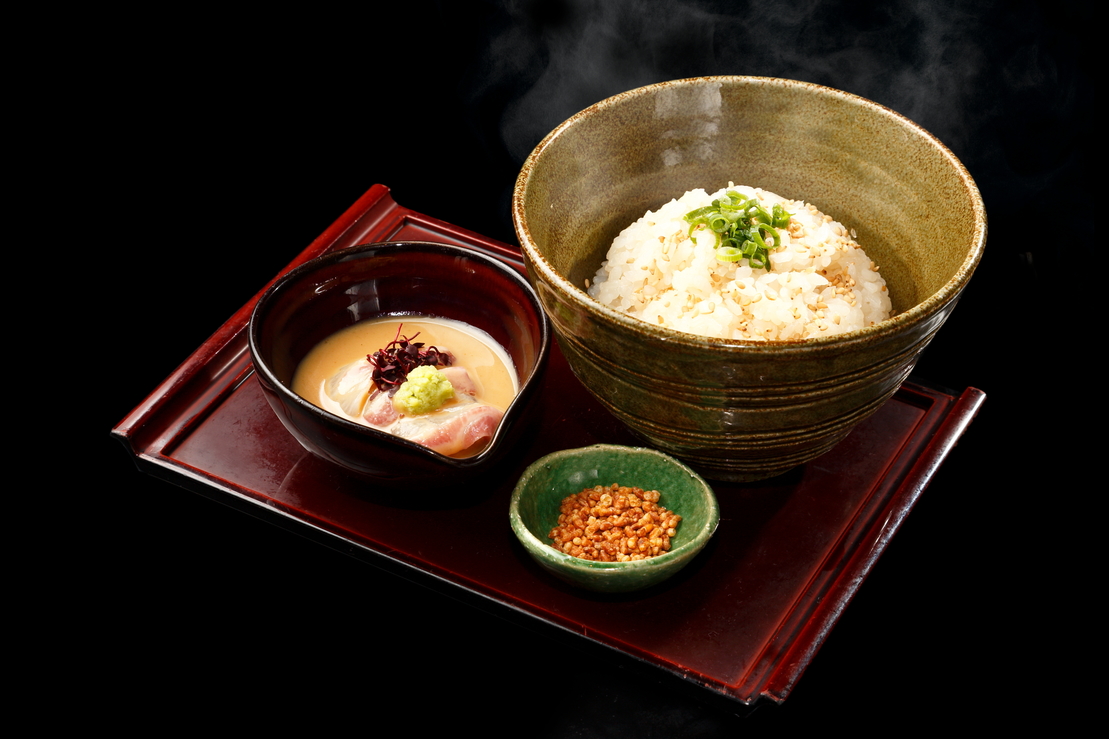 お盆に乗せられたふっくらご飯と胡麻ダレの真鯛の切り身にあられが添えられた鯛茶漬けセット